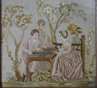 A framed and glazed 19th century silk embroidery of three people playing backgammon in a garden with