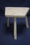 AN ANTIQUE WHITE PAINTED MILKING STOOL