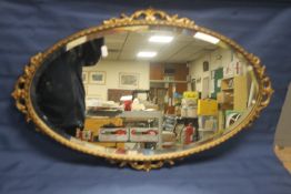 AN OVAL GILT ORNATE MIRROR 75 CM X 48 CM
