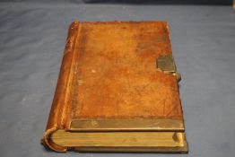 AN ANTIQUE LEATHER BOUND LEDGER WITH BRASS LOCK