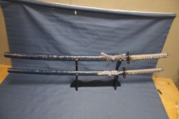A MATCHING PAIR OF REPRODUCTION SAMURAI SWORDS ON STAND