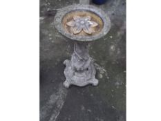 A CONCRETE BIRD BATH WITH A FLORAL THEME