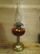 A VINTAGE BRASS AND RUBY GLASS OIL LAMP