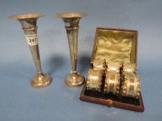A PAIR OF HALLMARKED SILVER BUD VASES TOGETHER WITH A CASED SET OF SIX WHITE METAL NAPKIN RINGS