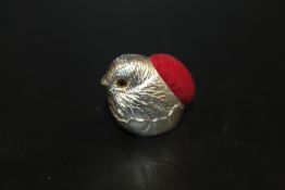 A WHITE METAL BIRD PIN CUSHION STAMPED STERLING