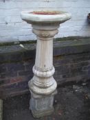 A RECTSITUTED STONE BIRD BATH ON CONCRETE PLINTH