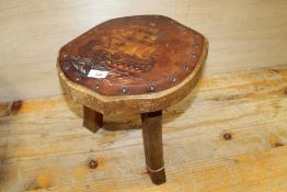A VINTAGE OAK MILKING STOOL WITH LEATHER TOP HAVING SAIL SHIP DETAIL