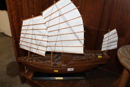 A WOODEN MODEL OF AN ORIENTAL JUNK ON STAND WITH MATERIAL SAILS