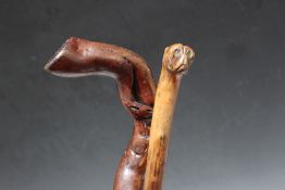 TWO FOLK ART WALKING STICKS, one carved in the style of a boxer dog head, L 85 cm