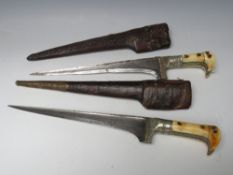TWO 19TH CENTURY EASTERN DAGGERS IN LEATHER SHEATHS, the bone handles with white metal decorations