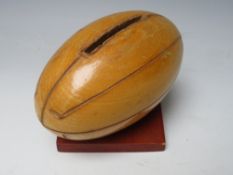 A VINTAGE WOODEN MONEY BOX IN THE FORM OF A RUGBY BALL, H 10 cm, L 12.5 cm