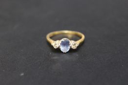 A HALLMARKED 18 CARAT GOLD SAPPHIRE AND DIAMOND RING, set with central light blue sapphire and two