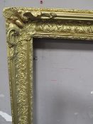 A 19TH CENTURY DECORATIVE GOLD FRAME WITH CORNER EMBELLISHMENTS, with some restoration, frame W 9.5,