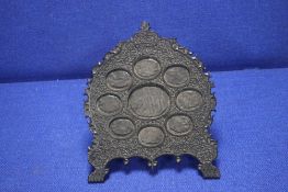 AN ANTIQUE ANGLO INDIAN CARVED HARD WOOD STAND FOR MINIATURES, WITH 9 OVAL APERTURES FITTED WITH