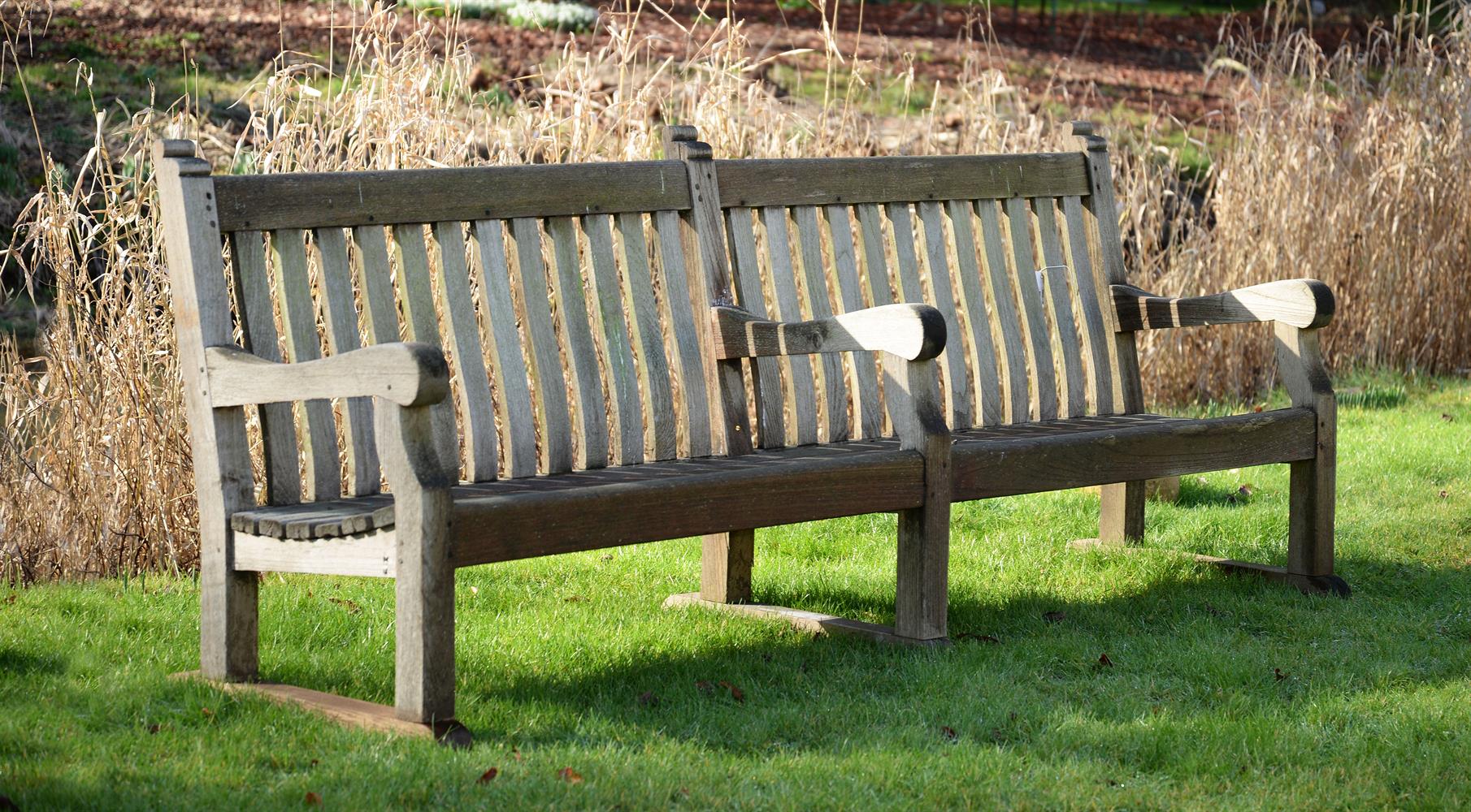 A LARGE WEATHERED HARDWOOD GARDEN BENCH, EARLY/MID 20TH CENTURY