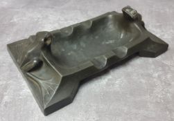 An Arts & Crafts pewter novelty frog ashtray, the two frogs sat astride each end with elongated arms