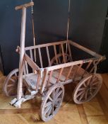 A rustic farmhouse pine dog cart, with steel rimmed wooden spoked wheels and articulated steering