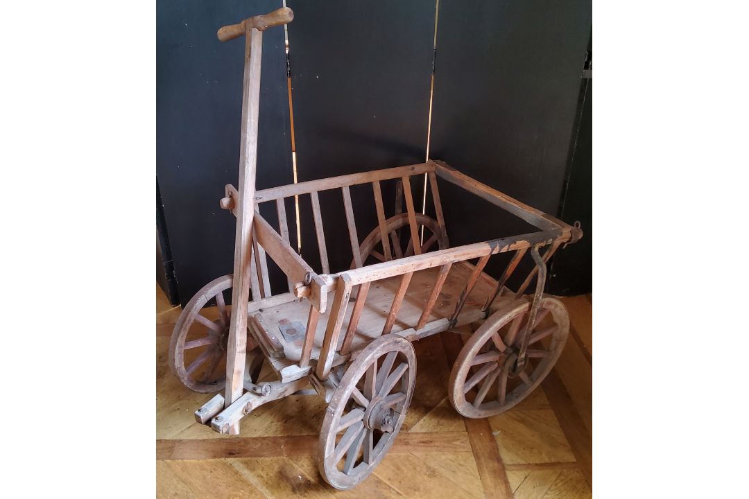 A rustic farmhouse pine dog cart, with steel rimmed wooden spoked wheels and articulated steering