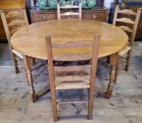 A Nigel Griffiths English oak circular gate leg drop leaf dining table with four matching rush