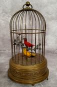 An early 20th Century birdcage automaton with decorative pressed brass base and cage containing