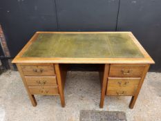 A 1940's oak knee-hole desk with green tooled leather inlaid top, five drawers. H77 x W137 x D76cm