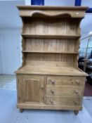 20th cent. Pine dresser the rack shaped cornice and sides, two shelves above a base with single door