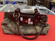 Fashion: Roberto Cavalli handbag. Woven body with gold printed accent flowers, faux leather