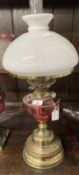 Victorian oil lamp brass base, cranberry glass reservoir, white shade marked Hinks's Duplex. 23½