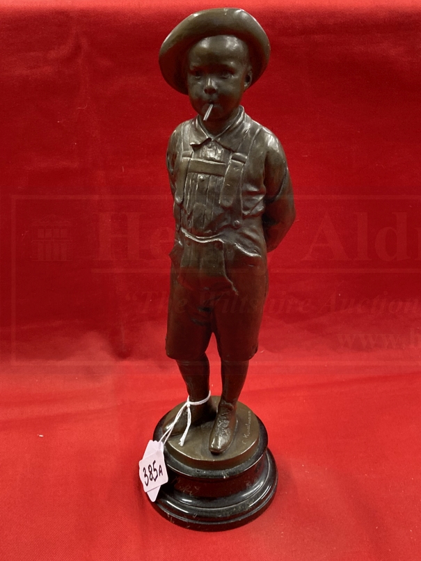 C. Kundonmann: Bronze figure of a boy smoking a Cheroot raised on a black marble base, signed C.
