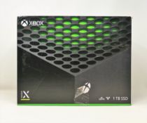 A pre-owned boxed Xbox Series X 1TB games console in black.