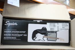 A Squier Stratocaster electric guitar, a Squire Frontman 10G and accessories.