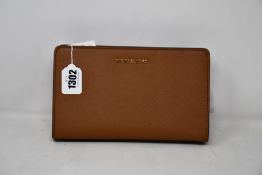 An as new Michael Kors crossbody clutch in brown.