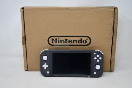A refurbished Nintendo Switch Lite games console in grey with UK charger and DC super villains