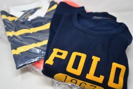 An as new Ralph Lauren Bleeker down jacket in orange, a rugby top and a sweatshirt (All XL).