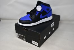A pair of youths as new Air Jordan 1 Mid with authentication tag (UK 5.5).