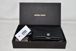 A Bottega Veneta Intrecciato leather passport holder with strap and box (Possibly pre-owned but