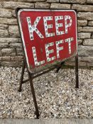 A Keep Left warning sign with integral glass reflectors, mounted in a freestanding frame.