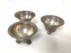 A near matching set of three white metal sorbet dishes with foliate decoration to rim, on ball