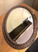An Edwardian oval wall mirror, with bevelled glass within a pierced frame (88cm x 64cm)
