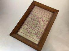 A 19th century alphabet and numbers sampler, worked in red and green threads, signed 