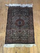 A silk-ground rug of Persian design, with all-over floral design centred by a concentric