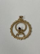 A 9ct London gold pendant of circular form with horned animal and single red stone, measures 3.5cm