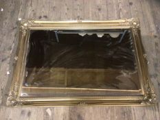 A modern wall mirror, the rectangular bevelled edge within a gilt frame, measures 75cm x 107cm