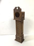 A treen miniature long case pocket watch stand in clock form with carving to case and body, possibly