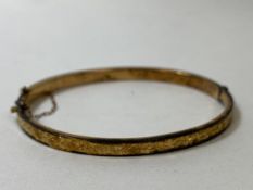 An Edwardian 9ct gold bangle, Birmingham, foliate engraving to one side, (7cm d), weighs 5.52