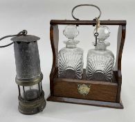 EDWARDIAN OAK TANTALUS & MINER'S LAMP, tantalus with two moulded glass spirit decanters (one with