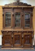 RENAISSANCE-STYLE FLEMISH OAK TRIPLE BOOKCASE, glazed doors bewteen lions mask and angel uprights,