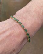 YELLOW METAL DIAMOND & EMERALD BRACELET, having twenty-six oval cut emeralds alternating with