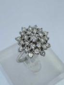 18CT WHITE GOLD DIAMOND CLUSTER RING, the central diamond (0.15cts approx.) surrounded by a