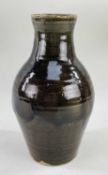 A STUDIO POTTERY STONEWARE VASE of baluster form with narrow neck flared at rim, in deep brown-green